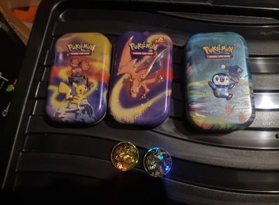 Three Pokemon tins with two coins.