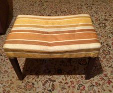 Vintage footstool which has wooden legs.