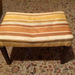 Vintage footstool which has wooden legs.