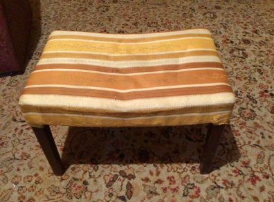 Vintage footstool which has wooden legs.