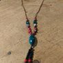 This Bohemian-style necklace features a prominent central blue bead with a leaf-shaped tassel. Image 2