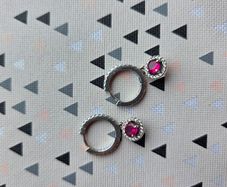 A beautiful pair of  sterling silver hoop earrings featuring small encrusted zircons and a dazzling ruby pink halo pendant.