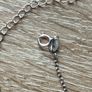 A silver bracelet with a heart-shaped pendant featuring a horse and foal's head. Image 6