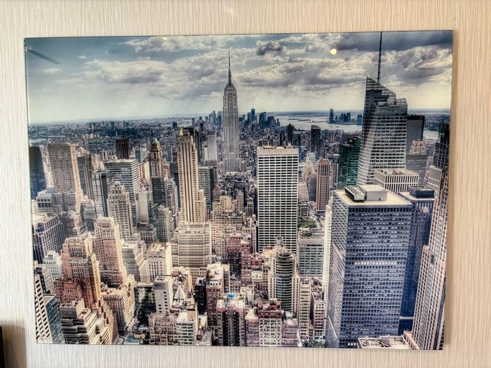 This glossy acrylic/glass wall art print features an aerial view of the New York City skyline with the Empire State Building