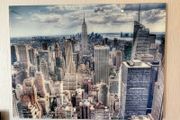 This glossy acrylic/glass wall art print features an aerial view of the New York City skyline with the Empire State Building