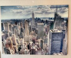 This glossy acrylic/glass wall art print features an aerial view of the New York City skyline with the Empire State Building