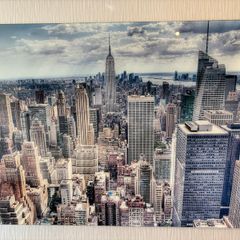 This glass wall art print features an aerial view of the New York City skyline with the Empire State Building
