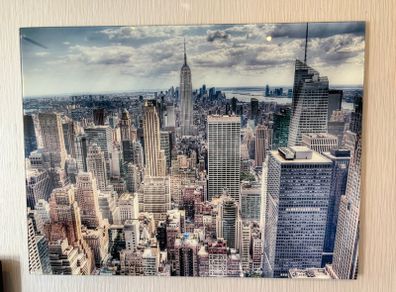 This glossy acrylic/glass wall art print features an aerial view of the New York City skyline with the Empire State Building