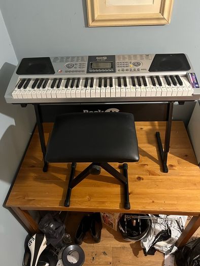 RockJam Electronic Keyboard Piano set up on a sturdy, matching heavy-duty Z-frame stand and an adjustable padded X-frame RockJam Keyboard Bench resting on a wooden surface.