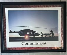 Framed Motivational Commitment Photo showing silhouette patient being loaded into helicopter by ambulance crew.