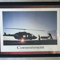 Framed Motivational Commitment Photo showing silhouette patient being loaded into helicopter by ambulance crew.