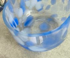A hand-blown blue and white swirl art glass piece Small glass bowl with sticker say The phrase "EVERY PIECE IS UNIQUE" circles the clover.