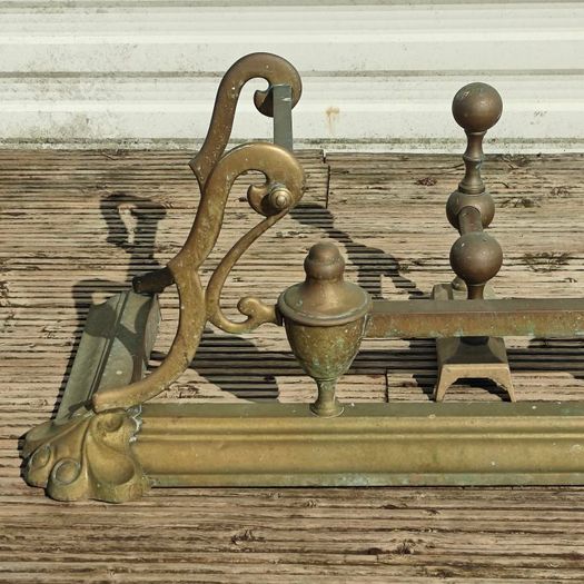 Art Nouveau style cast brass hearth fender with a pair of companion tool holders.