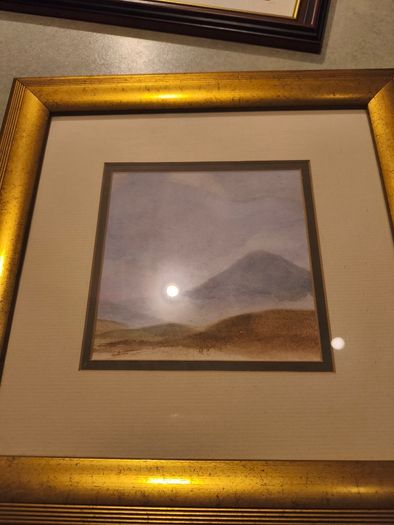 Gold framed picruer of land scape.
