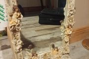 Rococo style wall mirror features a heavy, ornate resin frame decorated with carved cherubs and floral motifs