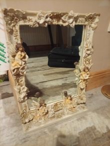 Rococo style wall mirror features a heavy, ornate resin frame decorated with carved cherubs and floral motifs