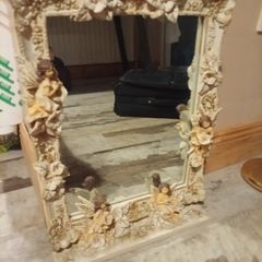 Rococo style wall mirror features a heavy, ornate resin frame decorated with carved cherubs and floral motifs