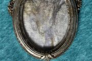 vintage-style oval picture frame in silver with a tassel and ribbon hanger