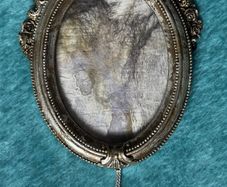 vintage-style oval picture frame in silver with a tassel and ribbon hanger