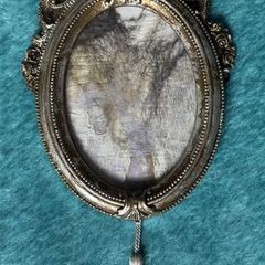 vintage-style oval picture frame in silver with a tassel and ribbon hanger