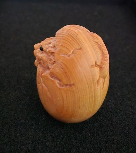 Carved wooden dragon hatching from an egg.