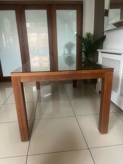 Brown wooden dining table with glass top