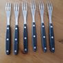 A 12-piece stainless steel steak knife and fork set with wooden riveted handles. Image 7