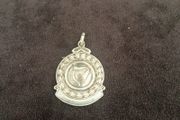 A silver medal or pendant depicting the Irish harp