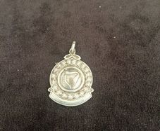 A silver medal or pendant depicting the Irish harp