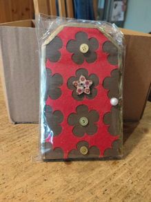 handcrafted wooden  Fairy door with red cardstock, brown flower cutouts, and decorative buttons.  various buttons acting as handles or embellishments.