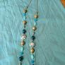 long, colorful beaded necklace featuring a mix of wood, blue, and white floral beads. Image 2