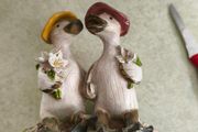 Decorative figurine featuring a duck couple setting on tree brunch.