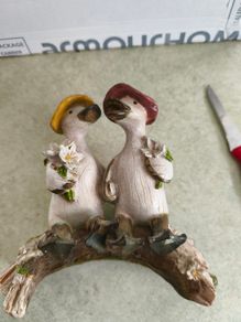 Decorative figurine featuring a duck couple setting on tree brunch.