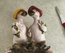 Decorative figurine featuring a duck couple setting on tree brunch.