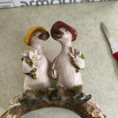 Decorative figurine featuring a duck couple setting on tree brunch.