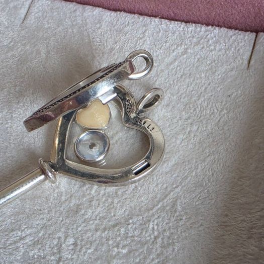 Pandora sterling silver key necklace with a heart,shaped floating locket and pink sparkling stones. Includes the two petite charms