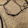 wooden pendant necklace featuring a dark brown wooden frame, a light-colored central bead, and a small dark yellow stone accent on an adjustable braided cord. Image 3