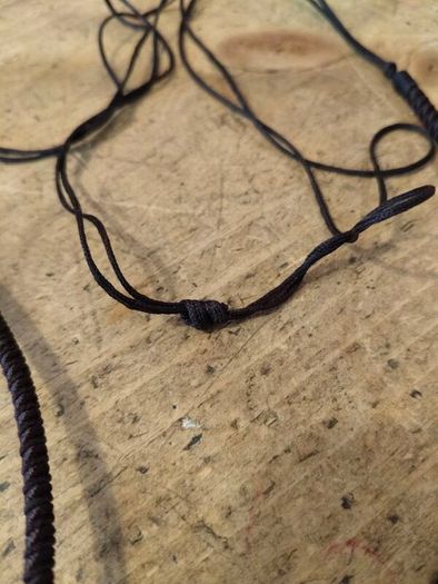 wooden pendant necklace featuring a dark brown wooden frame, a light-colored central bead, and a small dark yellow stone accent on an adjustable braided cord.