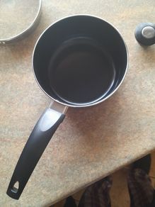 Brand new black saucepan with old lid