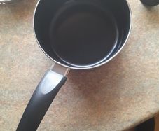 Brand new black saucepan with old lid