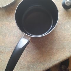 Brand new black saucepan with old lid