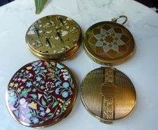 A Collection of Mid-Century Compacts. Tallent Enamel, Kigu, a Courting Couple Novelty Piece and a Henriette Pocket-Watch Compact