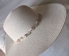 Beige wide-brim straw hat with a shell-adorned band.