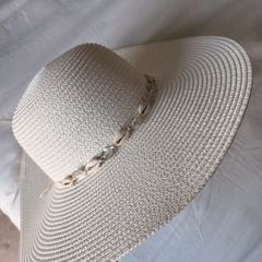 Beige wide-brim straw hat with a shell-adorned band.