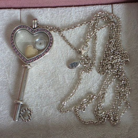 Pandora sterling silver key necklace with a heart,shaped floating locket and pink sparkling stones. Includes the two petite charms
